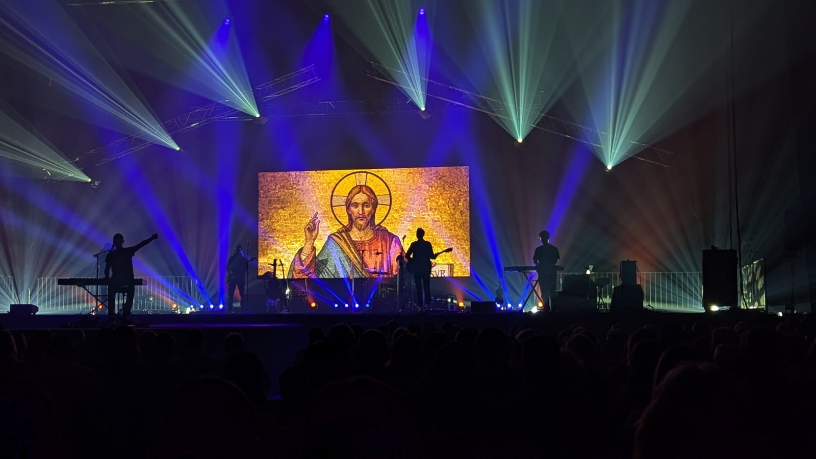 Glorious sur scéne le 6 décembre. Au fond de la scéne, un écran projette une image de Jésus.