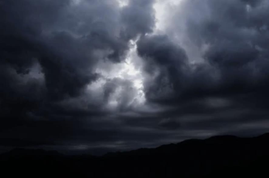 Un ciel gris, sombre, nuageux et menaçant avec une petite éclaircie qui tente de percer au travers des nuages.