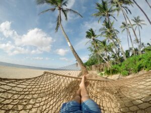 Un hamac accroché entre deux palmier sur la plage.