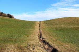Une prairie séparée en son milieu par une crevasse.