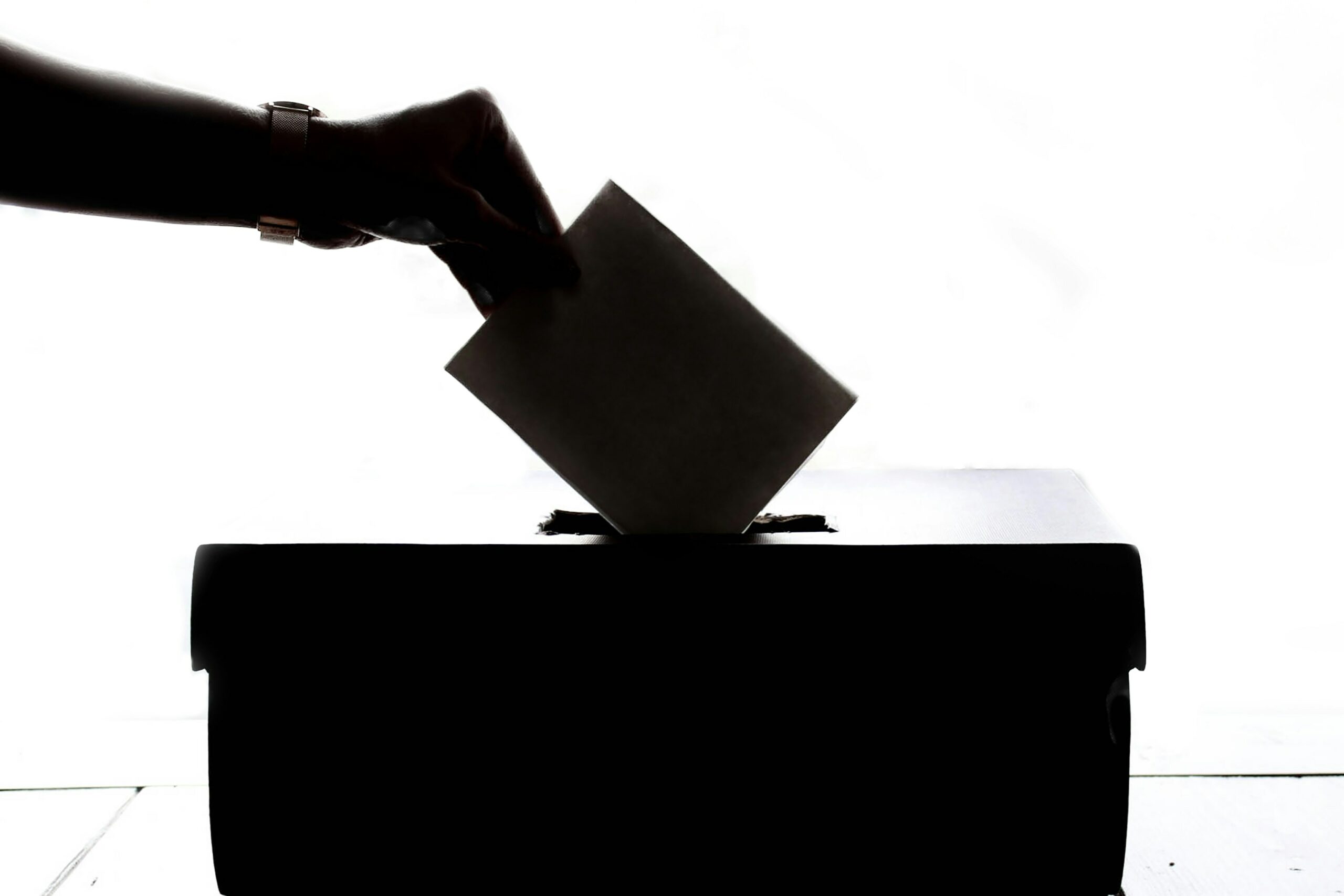 Une main glissant un bulletin de vote dans une urne.