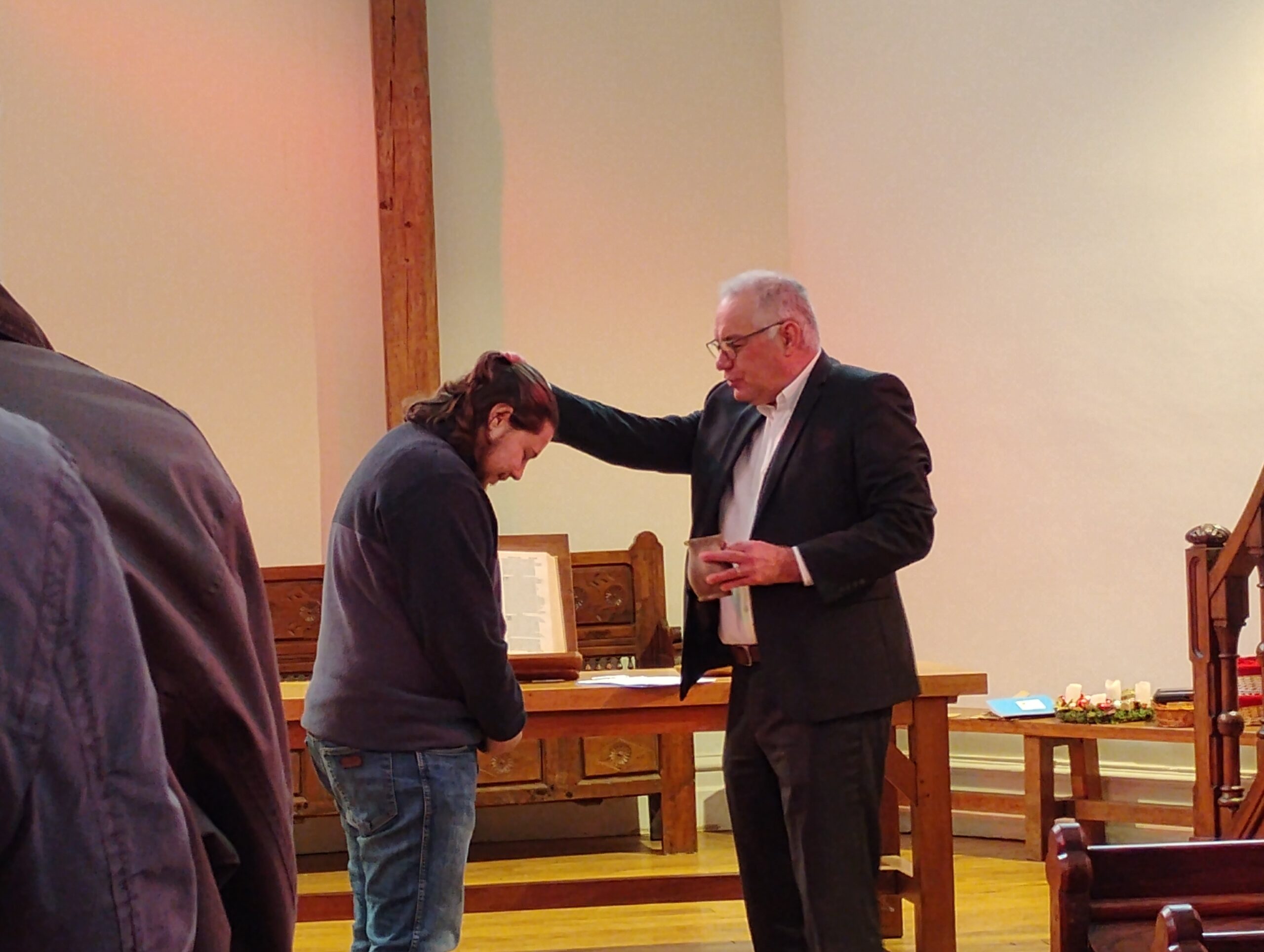 Le pasteur STÜCKER verse de l'eau sur la tête de Théo.