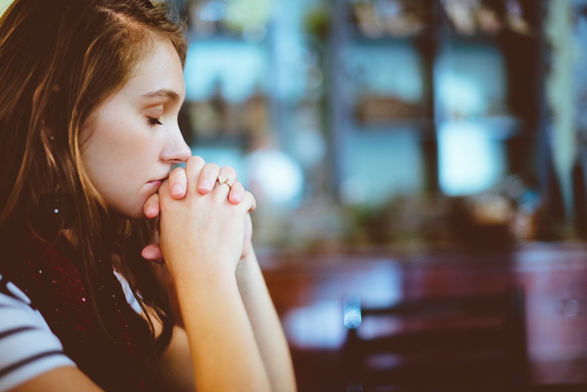 Une femme les mains jointes sur un banc dans une église